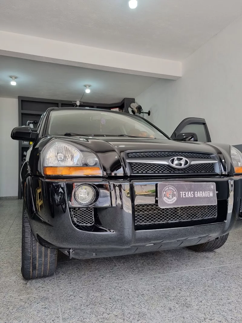 Hyundai Tucson preto no box da Texas Garagem, com a placa de identificação da marca em frente