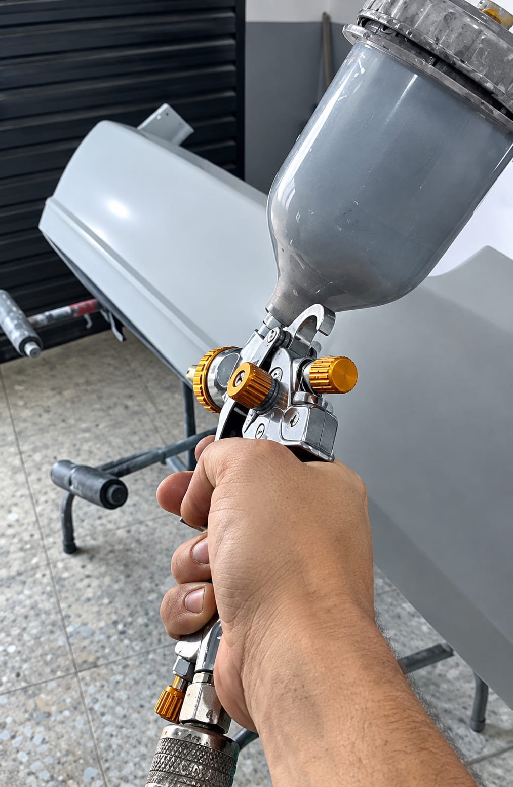 Profissional da Texas Garagem aplicando pintura com pistola em peça automotiva
